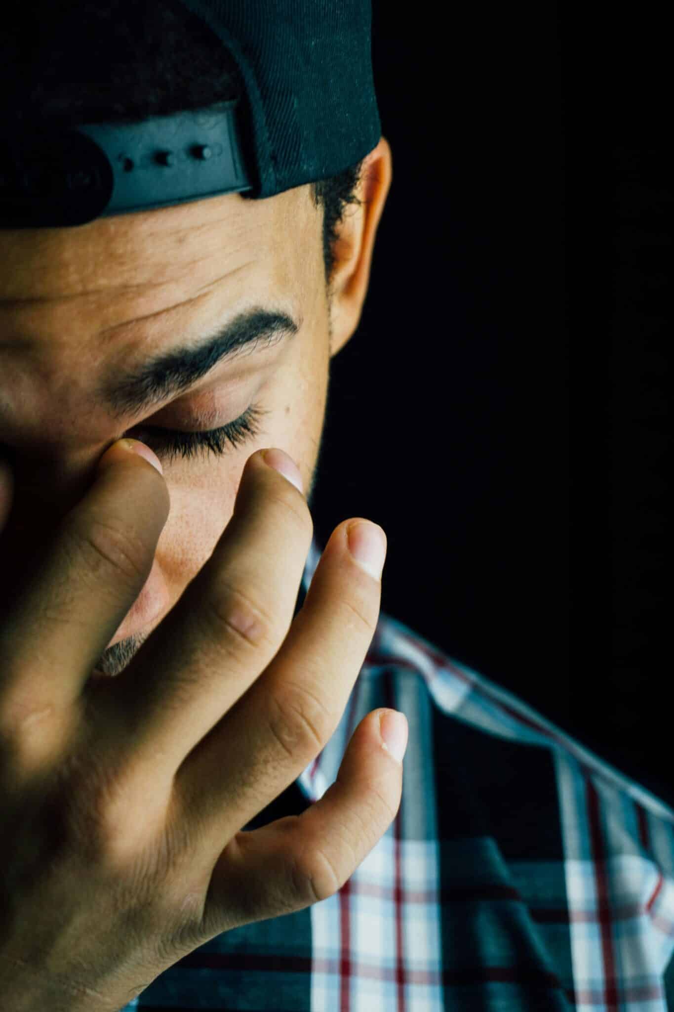 A close-up portrait capturing the emotional expression of a man in a dark studio setting.